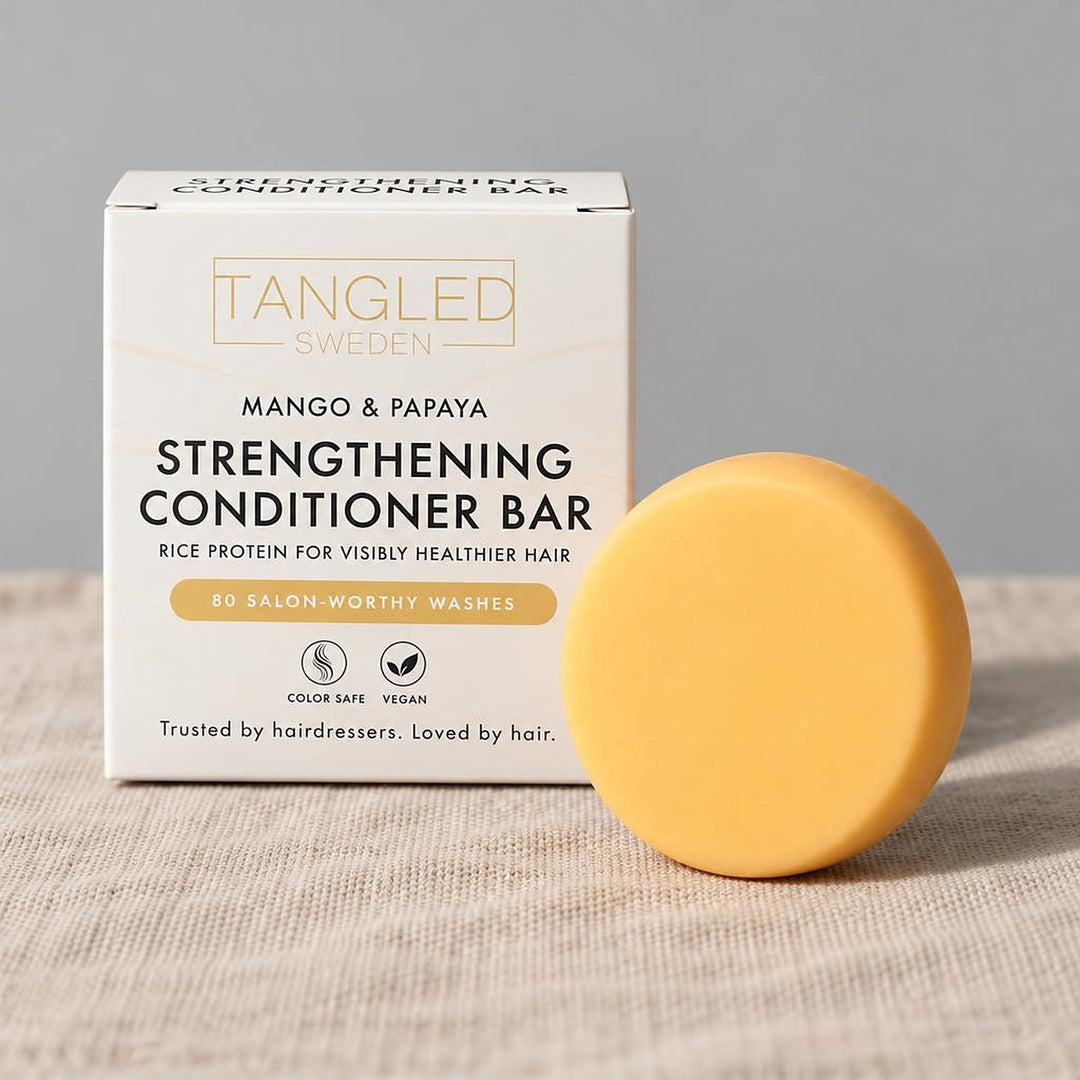 Tangled Strengthening Conditioner Bar with mango and papaya, with its box on linen