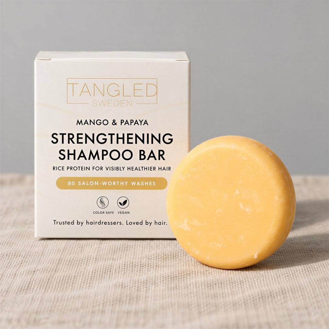 Tangled Strengthening Shampoo Bar with mango and papaya, with its box on linen